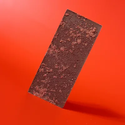 Dark Void Cosmic Crunch chocolate bar photographed on a red seamless background